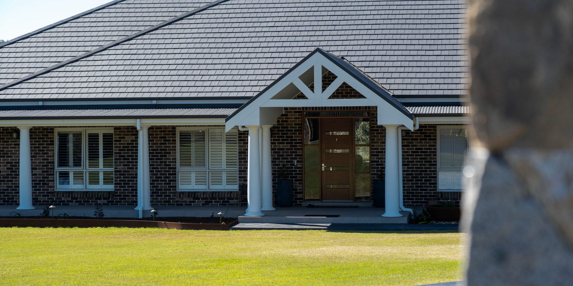 The entry gable, framed past a stone pier